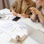 Two professionals reviewing financial reports and calculations at a desk, representing discussions and compliance related to superannuation accounting laws.